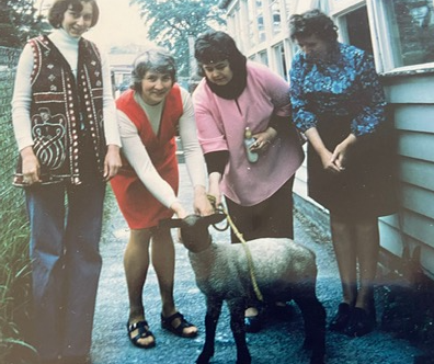 Playgroup staff and visitors with a sheep outside the building
