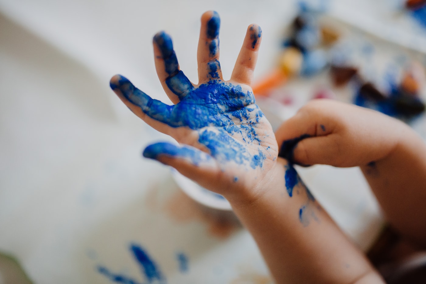 Close-up of a child's hand covered in blue paint during a craft session