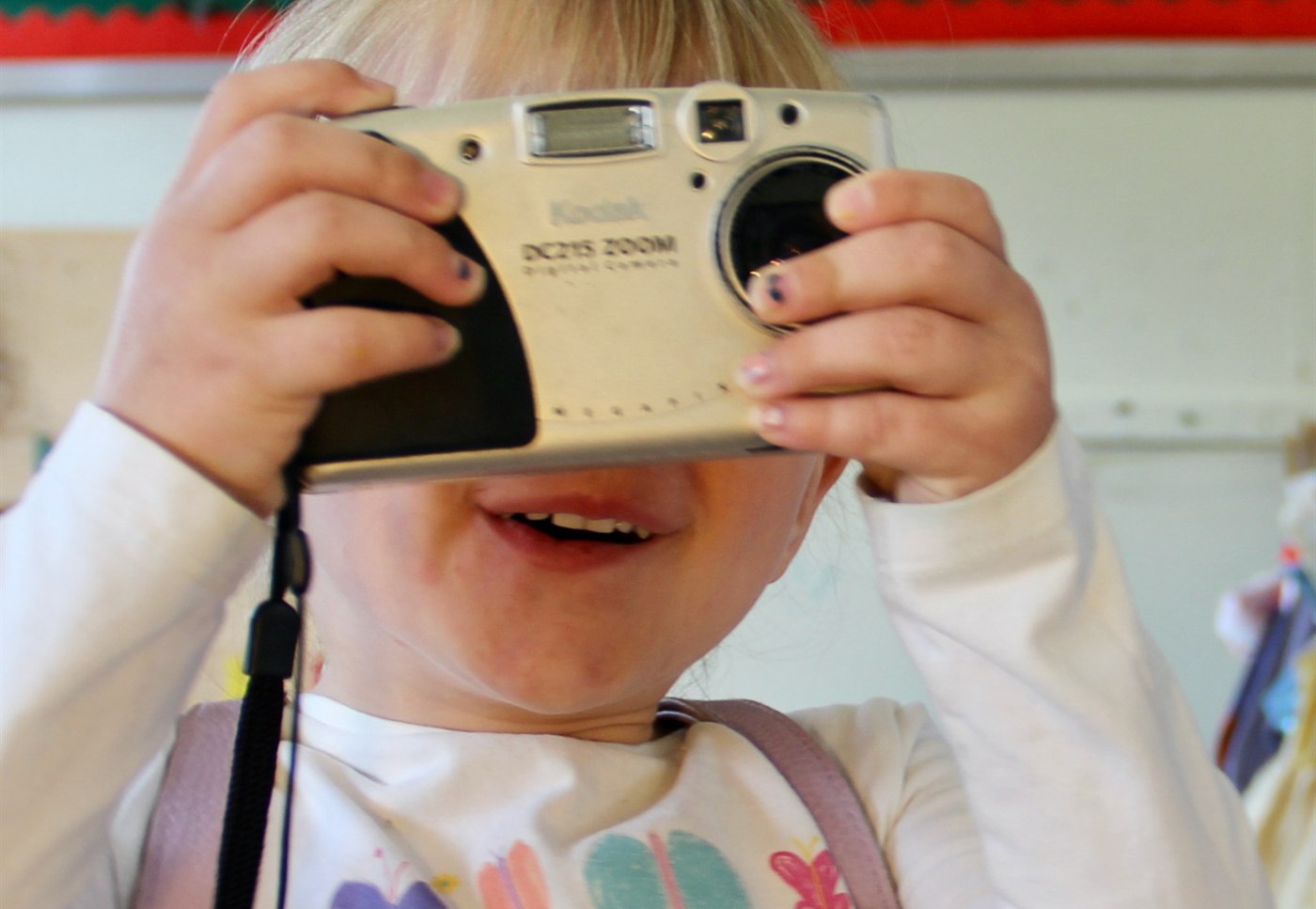Young child playing with a toy camera in a bright playroom