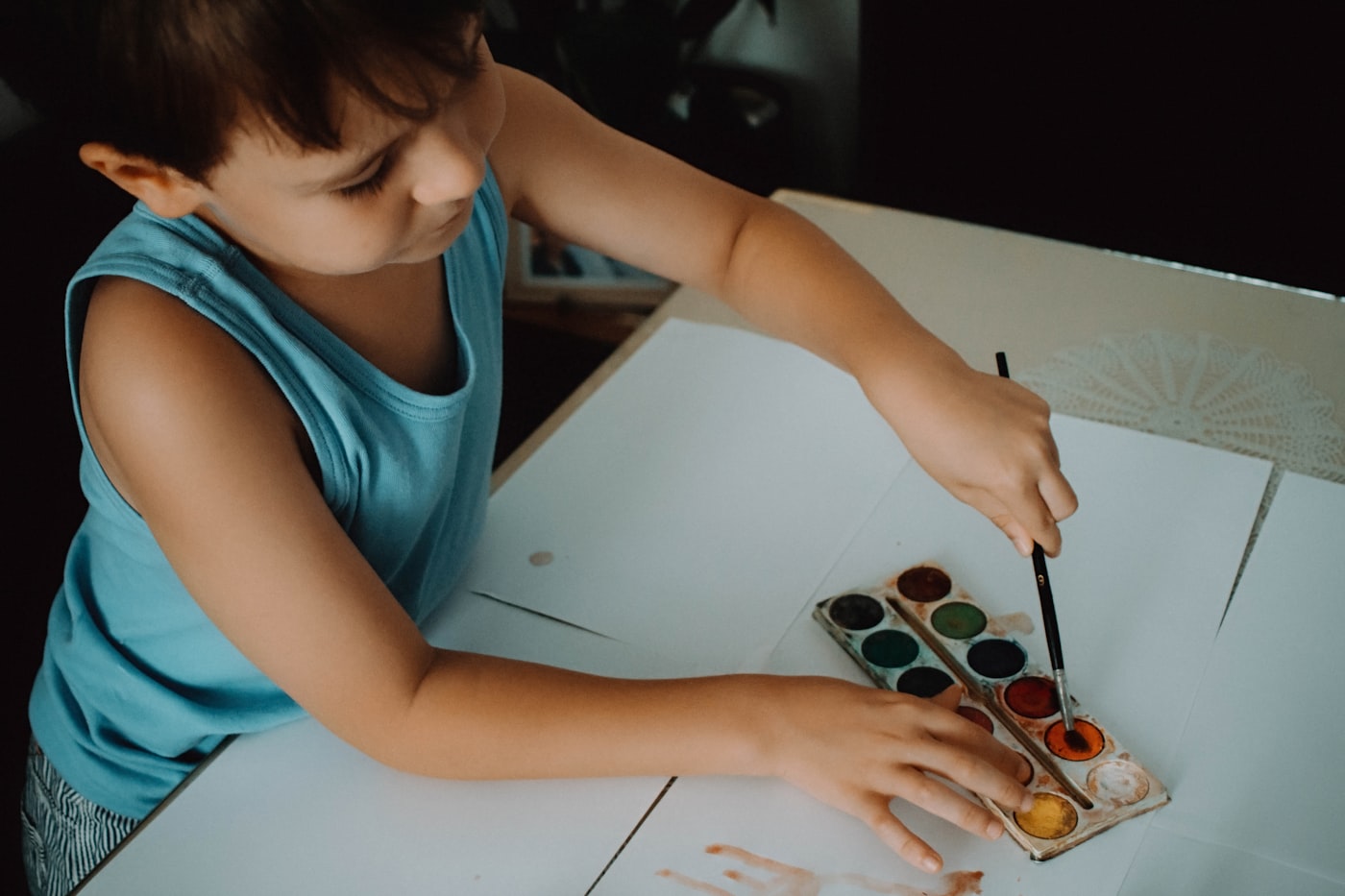 Child painting with watercolours at a table, reflecting our creative and playful environment